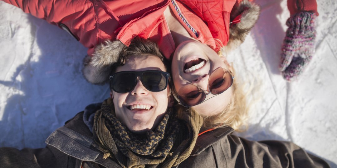 Caucasian couple in sunglasses smiling in snow