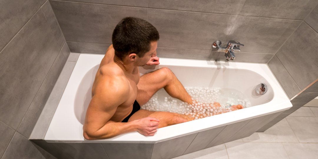 Man sitting in a bathtub filled with ice cubes